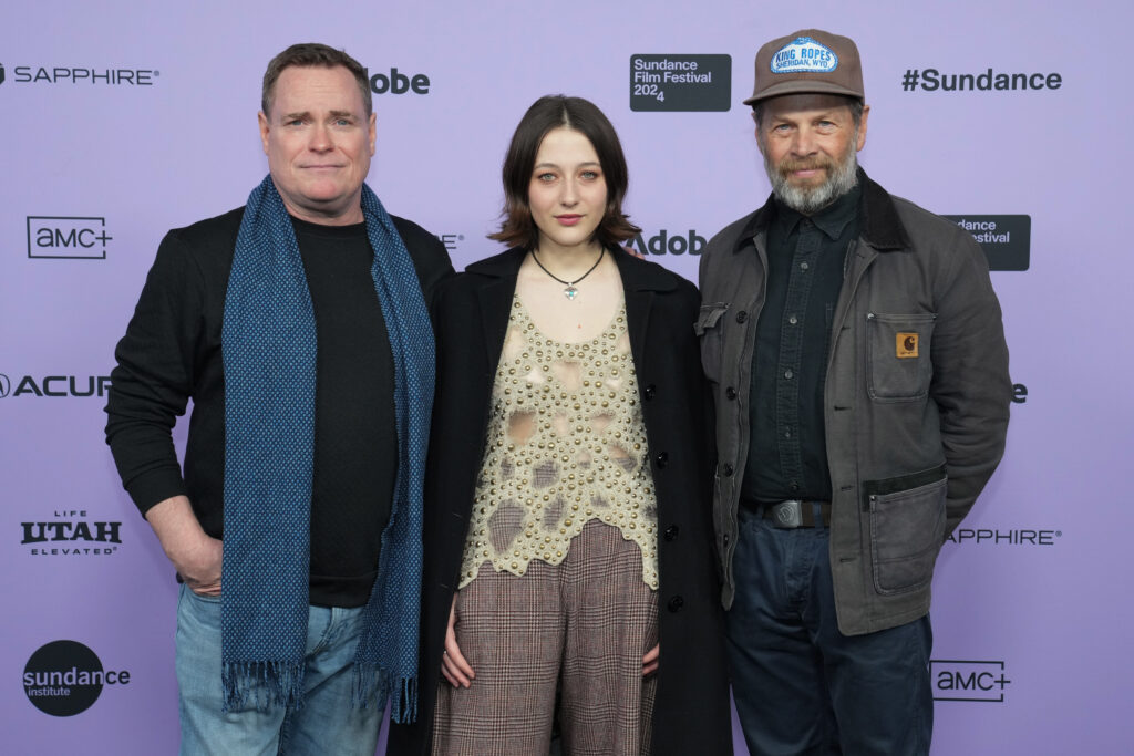 Danny McCarthy, Lily Collias, and James Le Gros pose together in front of a white 2024 Sundance Film Festival backdrop.