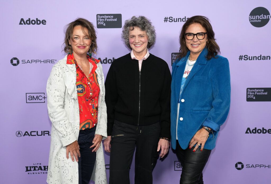 Sally Aitken, Terry Masear, and Bettina Dalton stand in front of a white 2024 Sundance Film Festival backdrop.