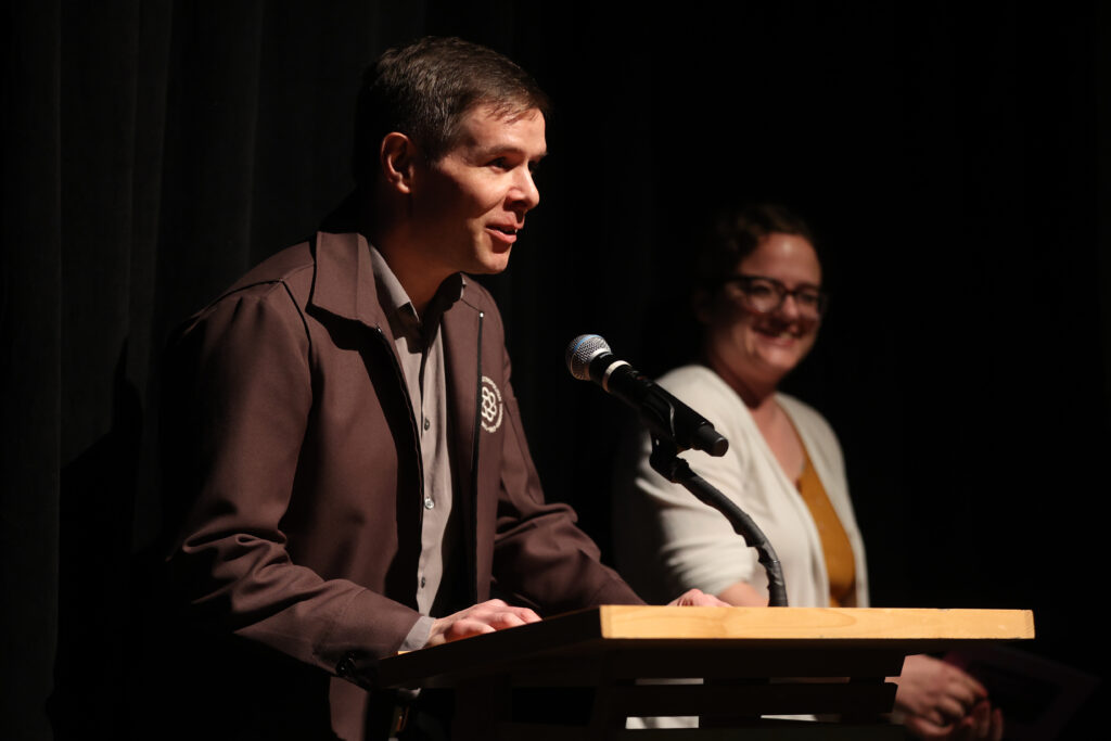 A white man with a brown speaks into the mic at The Library Theatre in Park City